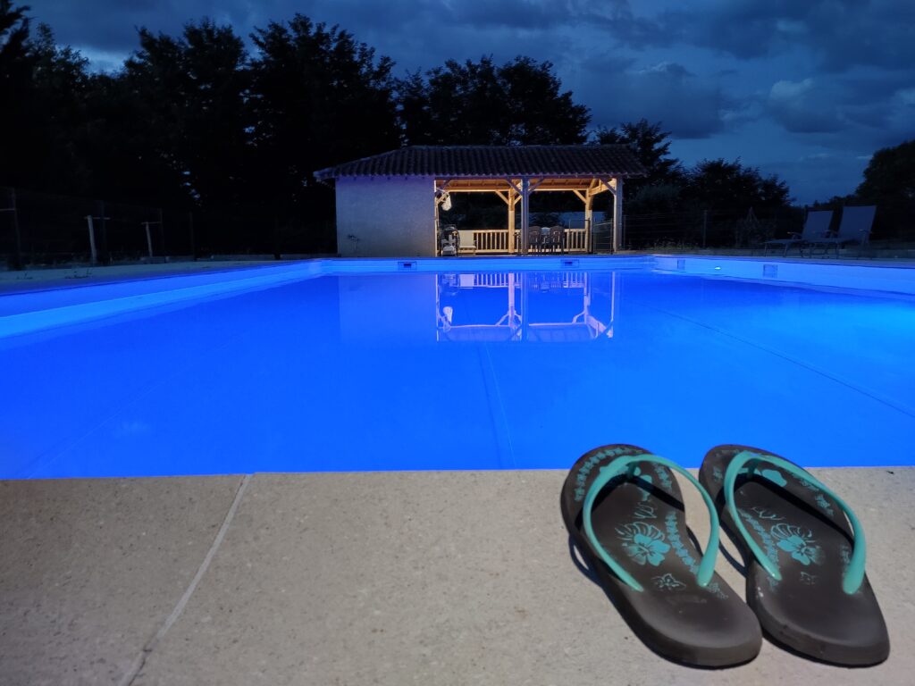une grande piscine aux belles couleurs bleues avec des tongs sur le bord